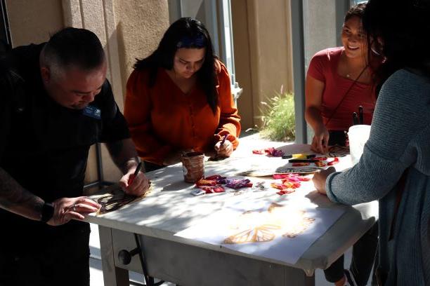 Students color butterflies for the Dreams have no borders mural