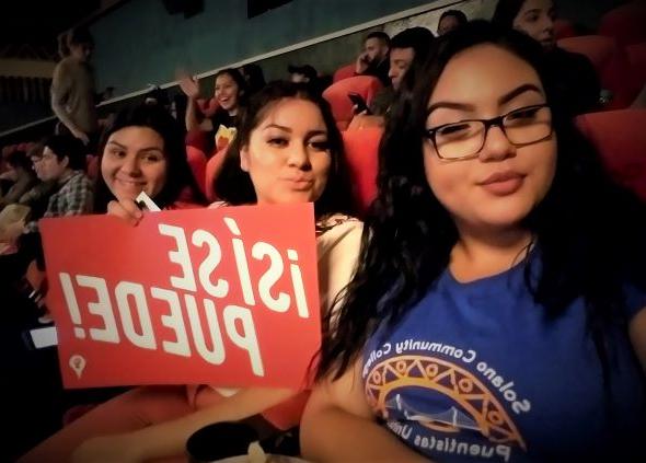 Three Puentistas Listening to Dolores Huerta holding a sign that says si se puede.